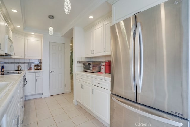 kitchen with freestanding refrigerator, tile countertops, white cabinetry, and white microwave
