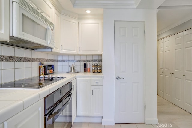 kitchen featuring tasteful backsplash, black appliances, tile countertops, and white cabinetry