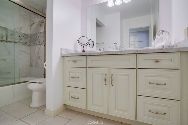 bathroom with tile patterned flooring, vanity, shower / bath combination with glass door, toilet, and baseboards