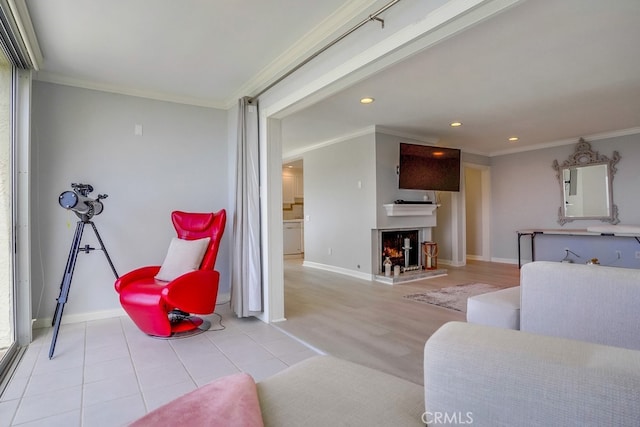 living area featuring crown molding, baseboards, and a warm lit fireplace