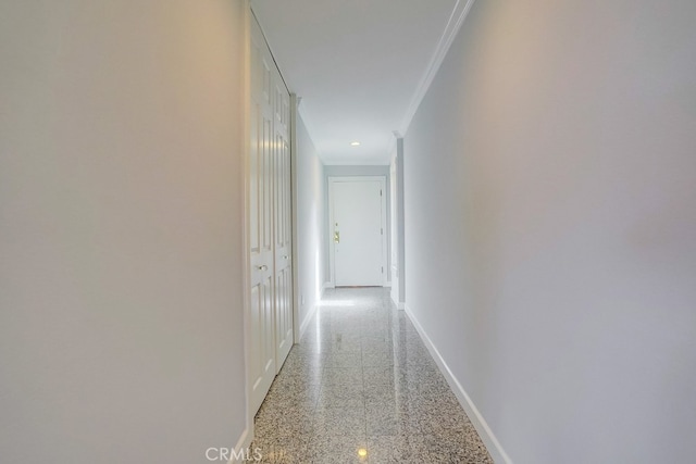 hallway featuring crown molding, baseboards, and light speckled floor