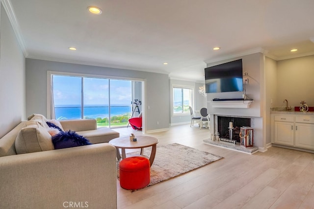 living room featuring recessed lighting, baseboards, ornamental molding, and light wood-style flooring