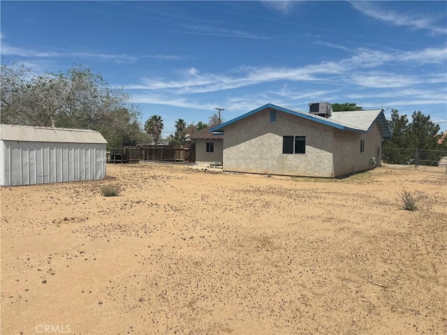 exterior space with fence, cooling unit, an outbuilding, and a storage shed