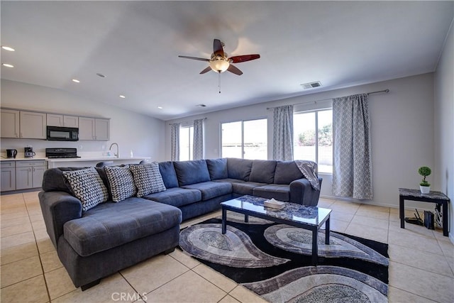 living area featuring light tile patterned floors, a ceiling fan, visible vents, and plenty of natural light