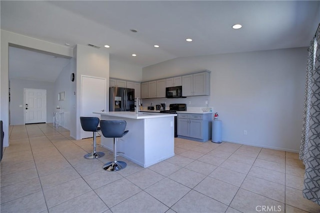 kitchen with stainless steel range oven, gray cabinetry, black microwave, refrigerator with ice dispenser, and lofted ceiling