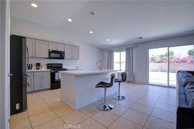 kitchen featuring light tile patterned flooring, gray cabinets, black appliances, open floor plan, and lofted ceiling