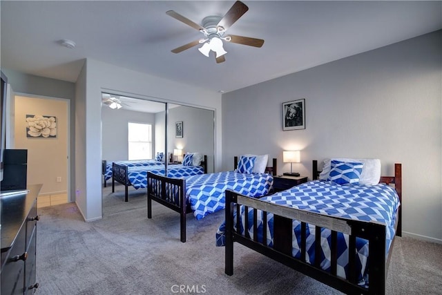 bedroom with baseboards, a ceiling fan, a closet, and light colored carpet