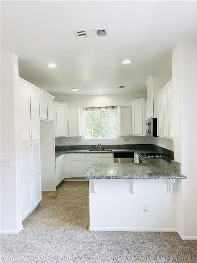 8054 Cresta Bella Rd, Rancho Cucamonga, CA 91730 - kitchen with visible vents, appliances with stainless steel finishes, a sink, a peninsula, and dark stone counters