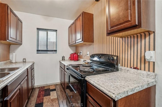 kitchen featuring a sink, light countertops, dark wood finished floors, and black range with electric cooktop