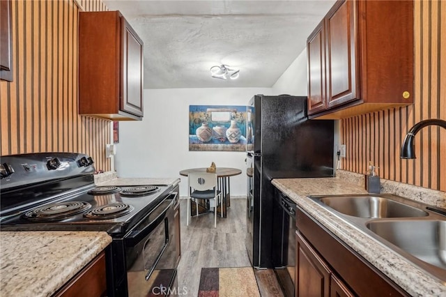kitchen featuring black appliances, light wood finished floors, a sink, and light countertops