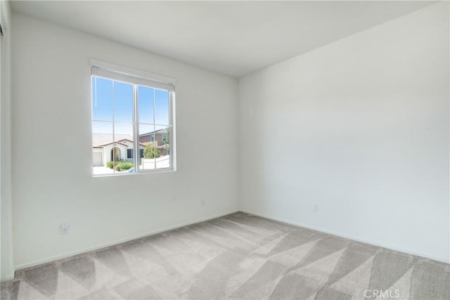 unfurnished room with baseboards and light carpet