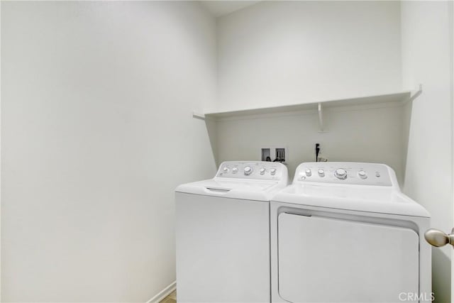 clothes washing area featuring baseboards, laundry area, and washer and clothes dryer