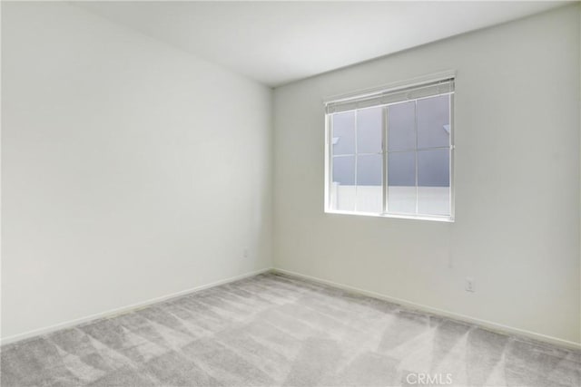spare room featuring baseboards and light carpet