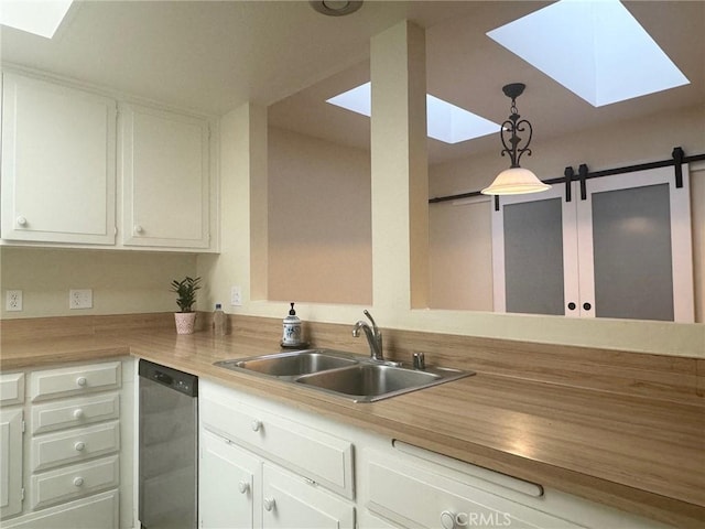 kitchen with a sink, white cabinetry, pendant lighting, stainless steel dishwasher, and a skylight
