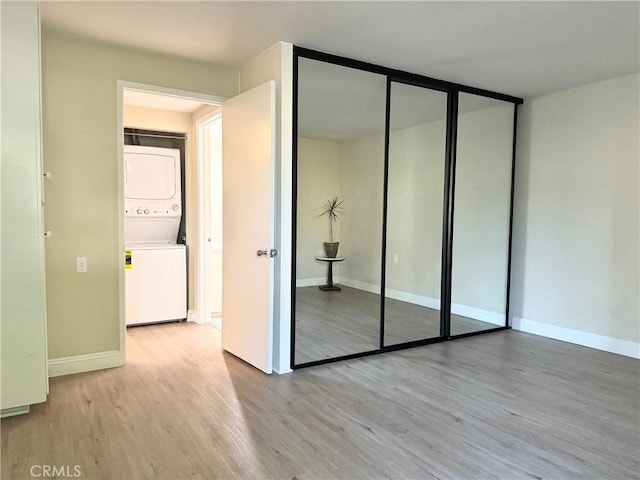 interior space featuring wood finished floors, stacked washer and clothes dryer, a closet, and baseboards