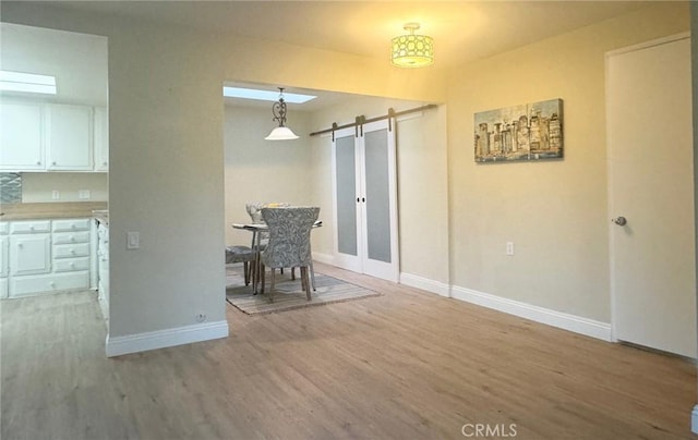 dining area with wood finished floors, a barn door, and baseboards