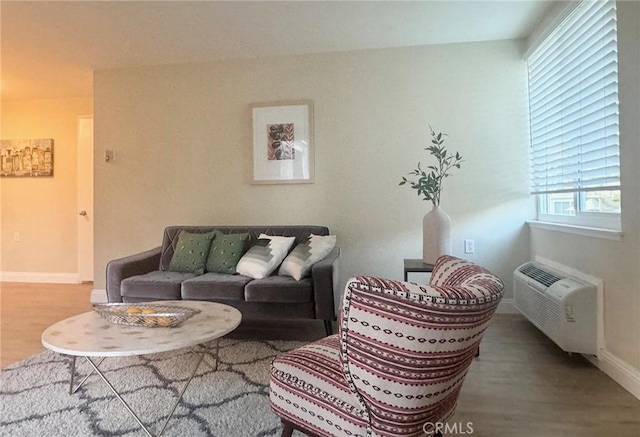 living area with a wall mounted air conditioner, wood finished floors, and baseboards