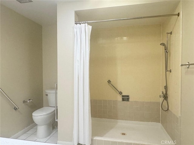bathroom featuring toilet, baseboards, tile patterned flooring, and tiled shower