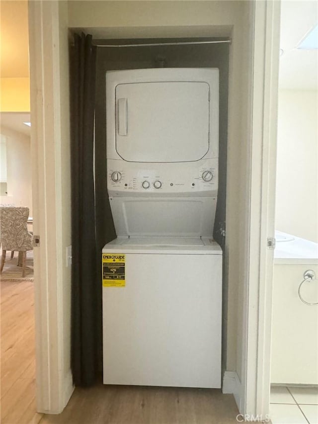 laundry room with stacked washing maching and dryer, light wood-type flooring, and laundry area