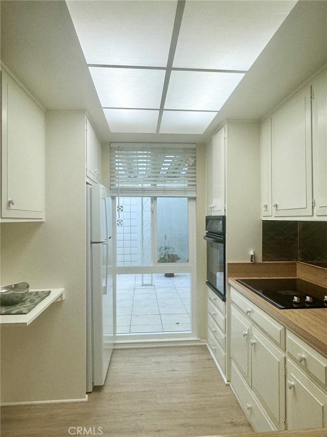 kitchen featuring white cabinets, black appliances, and light wood-style flooring