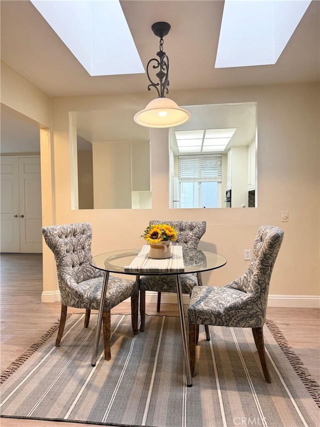 dining area featuring wood finished floors, baseboards, and a skylight