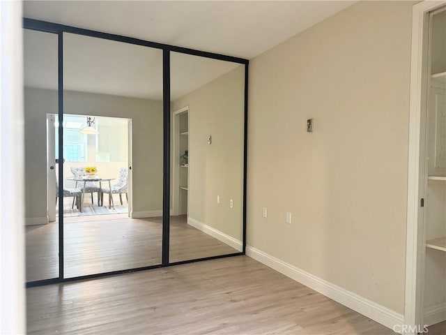 unfurnished bedroom with baseboards, light wood-style floors, and a closet