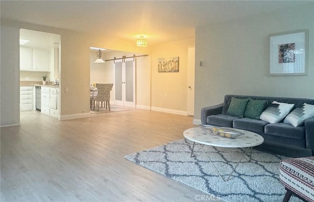 living area with wood finished floors, a barn door, and baseboards