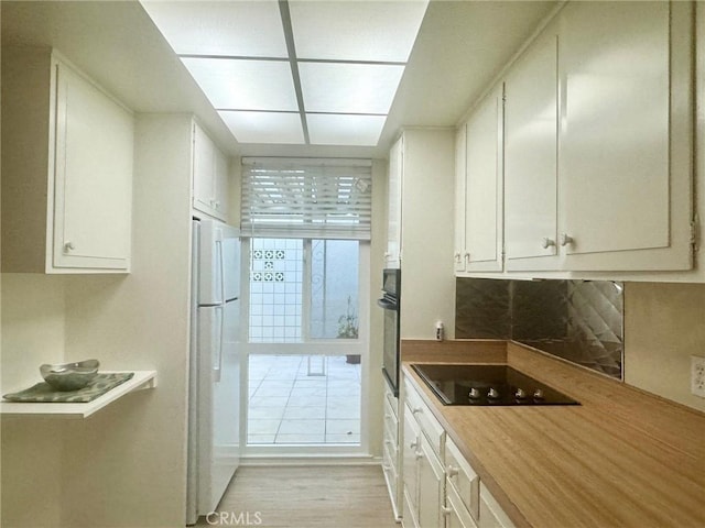 kitchen featuring black appliances, white cabinetry, decorative backsplash, and light wood-type flooring