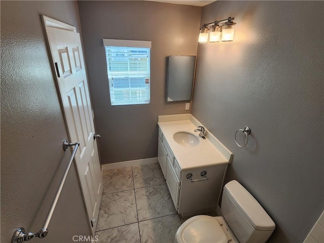 bathroom featuring toilet, marble finish floor, vanity, and baseboards