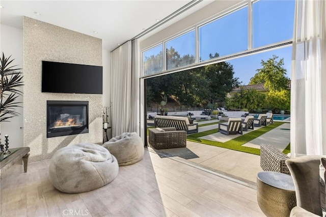 living area featuring wood finished floors and a glass covered fireplace