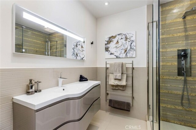 bathroom featuring a shower stall, tile walls, vanity, tile patterned flooring, and wainscoting