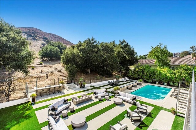 view of swimming pool with a patio area, outdoor lounge area, a mountain view, an infinity pool, and fence