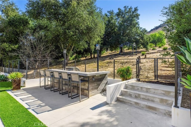 view of patio with fence and outdoor dry bar