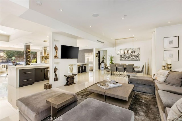 living room featuring light tile patterned flooring, recessed lighting, and a notable chandelier
