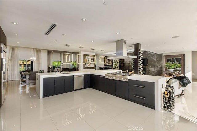 kitchen featuring appliances with stainless steel finishes, light countertops, dark cabinetry, island exhaust hood, and open floor plan