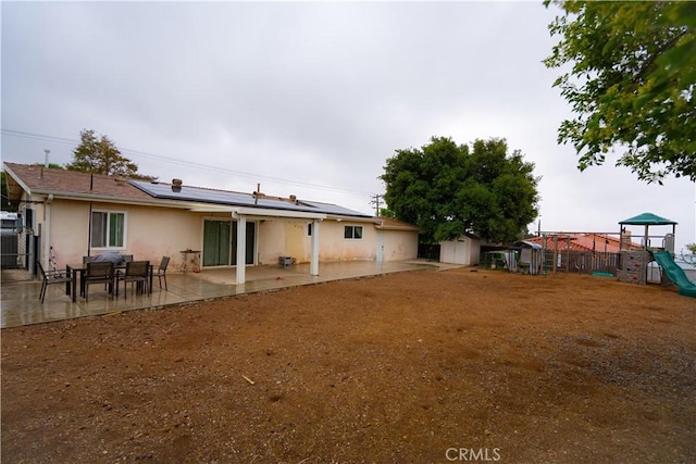 8491 Oak Glen Rd, Cherry Valley, CA 92223 - back of property featuring a playground, a patio, solar panels, and stucco siding