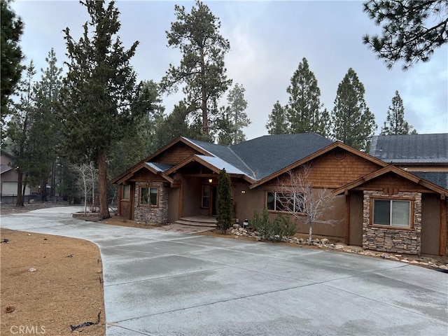 view of front of property featuring stucco siding, concrete driveway, and stone siding