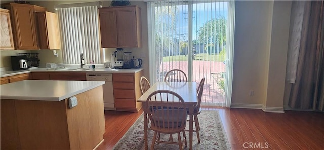 kitchen with wood finished floors, a sink, light countertops, and white dishwasher