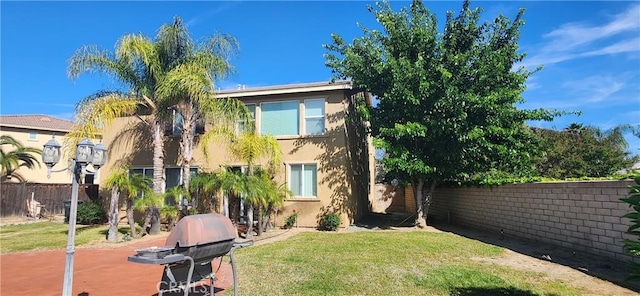 back of house with fence, stucco siding, and a yard
