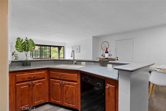 kitchen featuring black dishwasher, light wood finished floors, brown cabinetry, and a sink