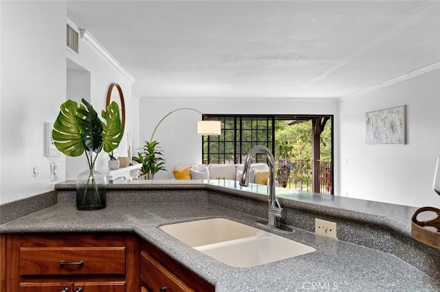 kitchen featuring crown molding, dark countertops, a sink, and visible vents