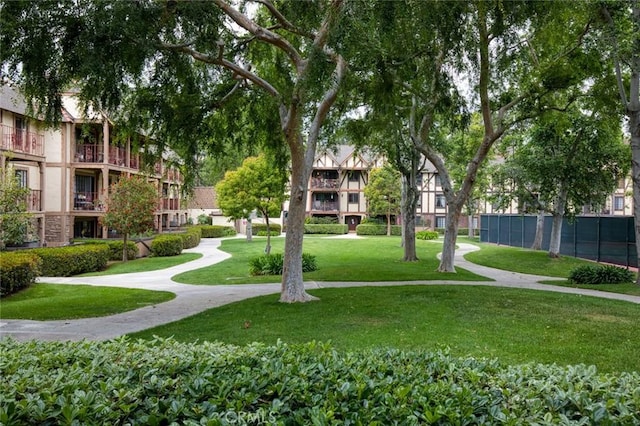 view of property's community featuring a lawn and fence