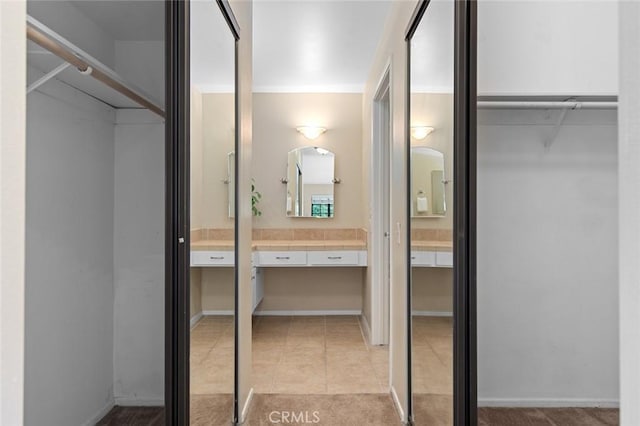bathroom with tile patterned floors, vanity, and a walk in closet