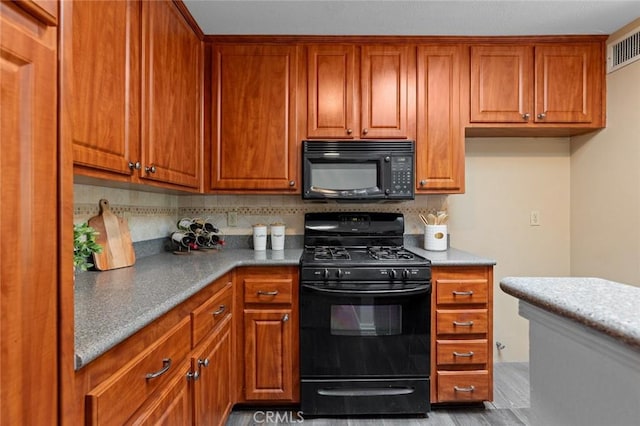 kitchen featuring visible vents, brown cabinetry, black appliances, and backsplash