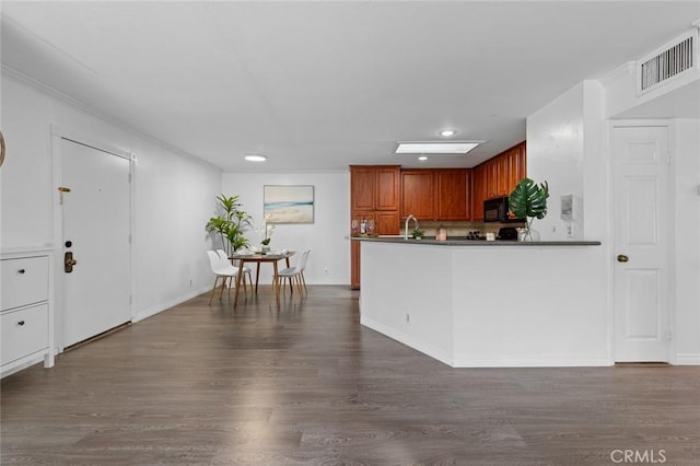 kitchen with visible vents, dark countertops, dark wood-style flooring, and a sink