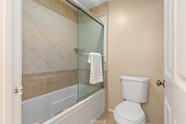 full bath with toilet, tile patterned flooring, shower / bath combination with glass door, and baseboards