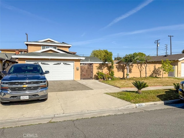 traditional-style house featuring a garage, a gate, driveway, stucco siding, and fence