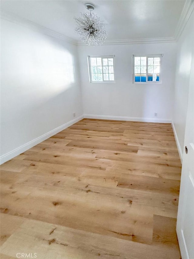 empty room with ornamental molding, wood finished floors, and baseboards
