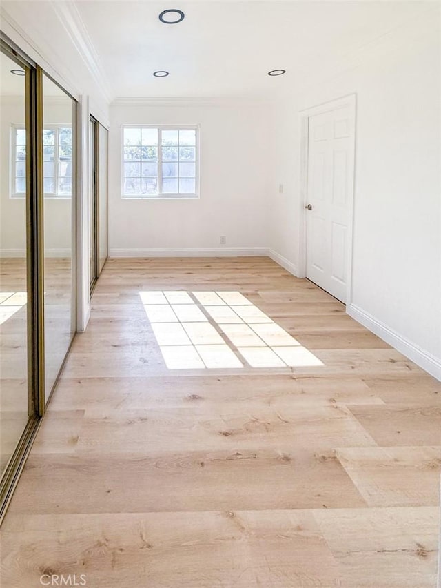unfurnished bedroom with baseboards, ornamental molding, and light wood finished floors