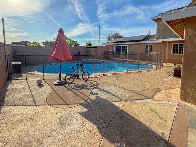 view of swimming pool featuring a fenced backyard, a pool with connected hot tub, and a patio area